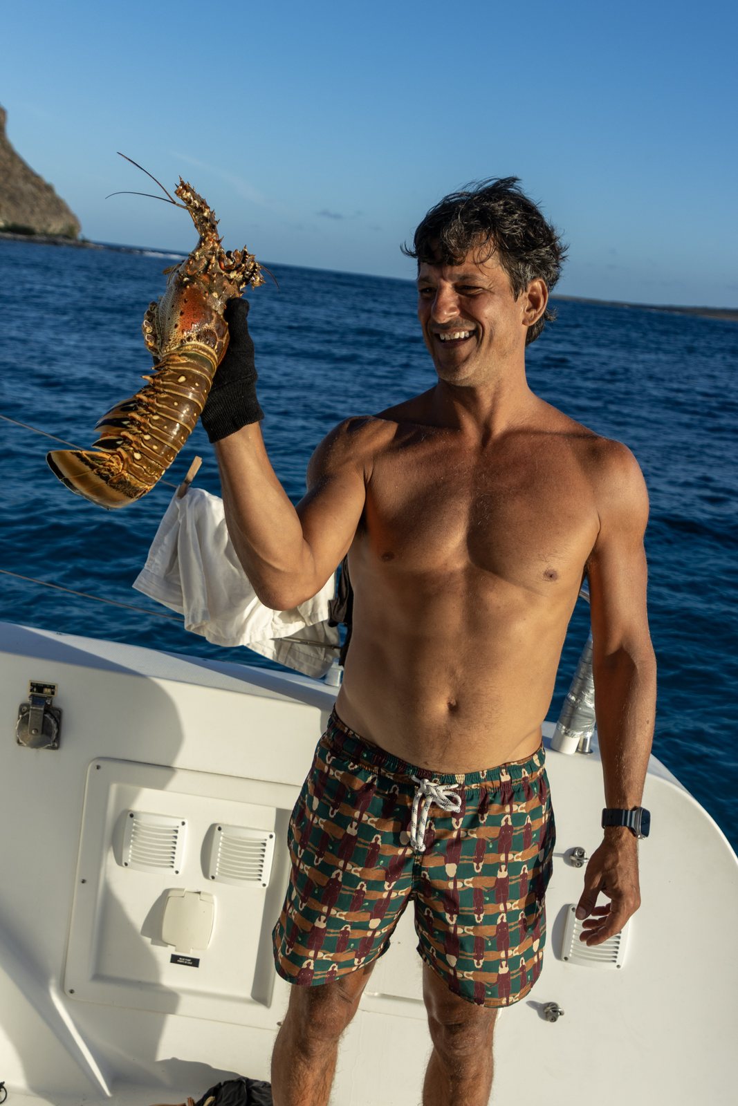 Guest holding up a freshly caught lobster on deck